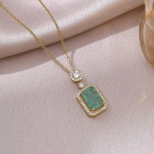 Elegante gouden ketting met smaragdgroen kristal en zirkonia op satijnen stof