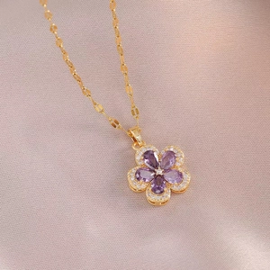 Collier fleur doré élégant avec zircons violets sur un fond texturé rose doux