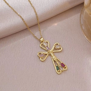 Gold crucifix necklace with colorful cubic zirconia and heart hollow design on silk background