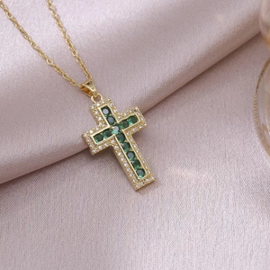 Elegant gold cross pendant necklace with green crystals and white zircon on silk fabric