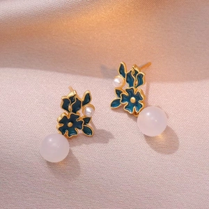Vintage floral stud earrings with blue enamel petals and pearls on pink silk display