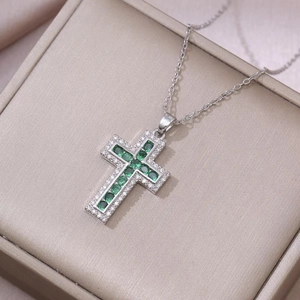 Vintage silver cross necklace with green zircon stones on a champagne jewelry box