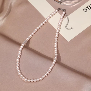 Elegant round pearl necklace with silver lobster clasp on champagne satin background
