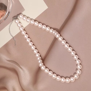 Elegant pearl necklace with silver lobster clasp on luxury rose silk background