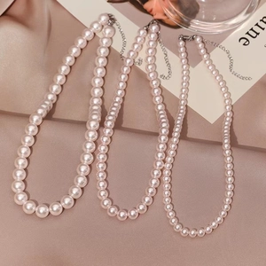 Three sizes of round pearl necklaces with adjustable silver clasps on brown satin