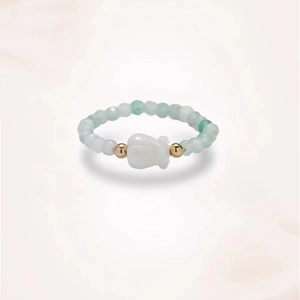 Détail de la bague en perles de jade vert clair avec une fleur en nacre blanche