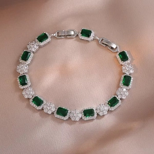 Macro shot of silver bracelet with emerald-cut green gemstones and zircon clusters