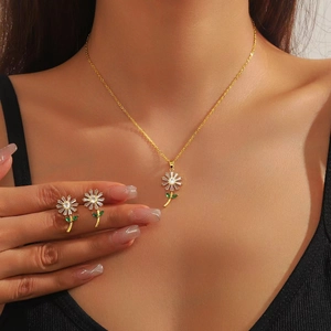 Elegantes Gold-Gänseblümchen-Schmuckset mit weißen Kristallen und grünen Edelsteinen