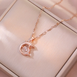 Detail view of a rose gold dolphin pendant with sparkling diamonds on a jewelry gift box