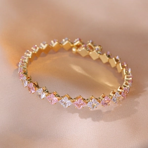 Nahaufnahme eines vergoldeten Tennisarmbands mit rosa und klaren Zirkonsteinen