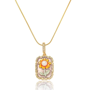 Detailansicht eines Blumenanhängers mit einer weißen Perle und gelber Emaille-Sonnenblume