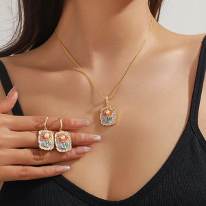 Detail eines floralen Emaille Schmucksets mit lila Hintergrund und Perlen am Modell