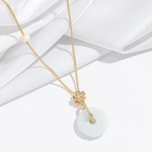 Close-up of gold necklace featuring a pearl, pavé clover, and white jade donut pendant