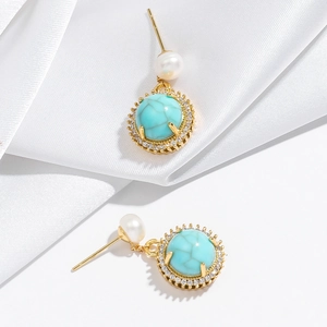 Detailed shot of vintage gold earrings with turquoise, pearls and zircon on silk