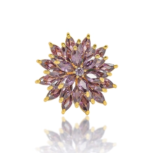 Vue macro d'une broche marguerite en cristal violet avec pierres marquises dorées
