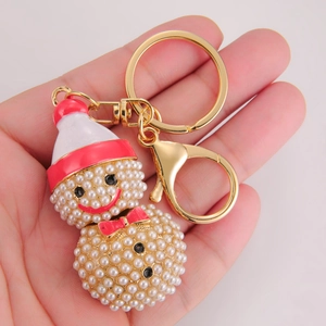 Niedlicher Weihnachts-Schneemann-Schlüsselanhänger mit weißen Kunstperlen in der Hand