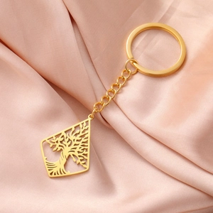 Detail of a golden tree of life keychain on pink silk fabric with a diamond hollow pendant