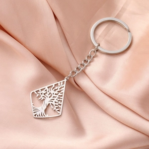 Close-up of tree of life hollow pendant on a stainless steel keychain over silk fabric