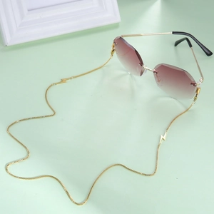 Detail showing gold chain with lightning bolt pendants on rimless brown gradient sunglasses