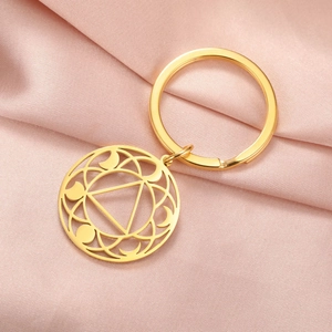 Detailed view of a golden geometric hollow circle keychain on pink silk fabric