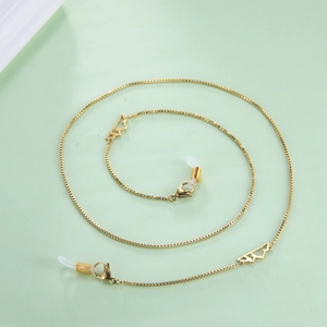 Golden box chain eyewear strap featuring hollow mountain pendants on green background