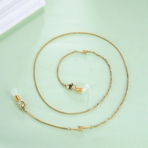 Detail of gold box chain sunglasses strap with lightning charms and silicone ends