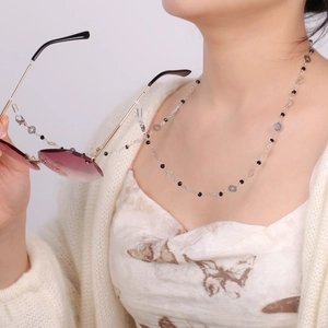 Chaîne de lunettes en métal argenté avec perles noires et breloques étoiles sur modèle