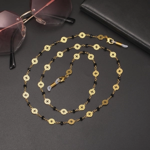 Détail de la chaîne de lunettes dorée avec anneaux évidés, perles noires et boucles silicone