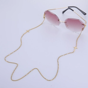 Détail de lunettes de soleil sans monture violettes avec chaîne à croix dorée
