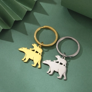 Golden and silver stainless steel polar bear keychain set on a green background