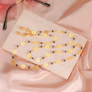 Détail de la chaîne de lunettes en métal doré avec cercles évidés et perles noires