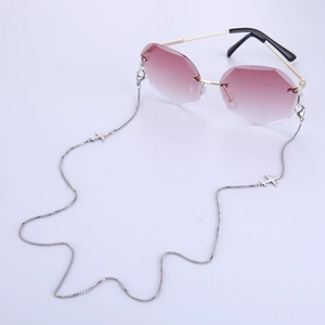 Détail de lunettes de soleil sans monture avec verres roses et chaîne argentée à pendentifs