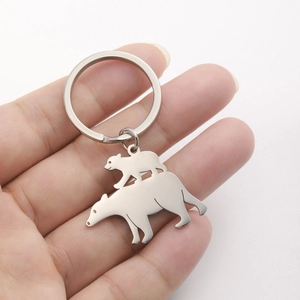 Polished stainless steel polar bear keychain pendant held in hand for scale