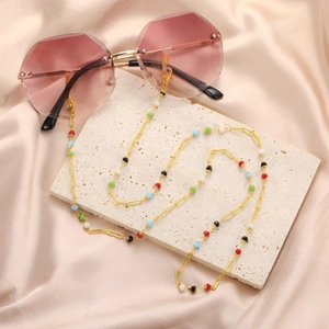 Detail der bunten Perlen Gold Brille Kette mit geometrischer randloser Sonnenbrille auf Seide