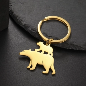 Macro detail of polished gold bear pendant keychain on a textured stone surface