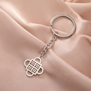 Silver stainless steel keychain with Adinkra symbol pendant on soft silk background