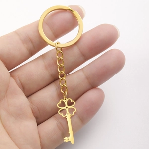 Golden stainless steel four-leaf clover keychain with hollow heart design held in hand