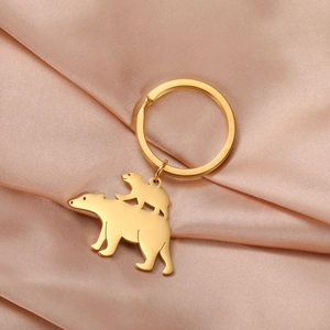 Macro detail of golden bear and cub keychain on elegant champagne satin fabric