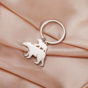 Polished stainless steel bear pendant keychain on a champagne silk fabric background