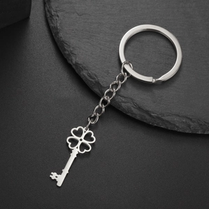 Close-up of a silver stainless steel four-leaf clover key pendant on black stone
