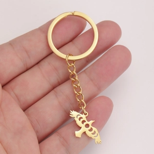 Detail of golden stainless steel keychain with hollow flying bird and moon phase pendant