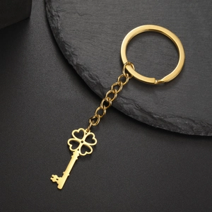 Detail of a golden stainless steel four-leaf clover key pendant with chain on stone