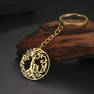 Détail d'un porte-clés Arbre de Vie doré avec breloques familiales sur un support en bois brut