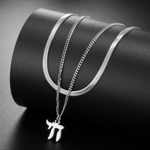 Detail van zilveren gelaagde slangketting met Chai-hanger op een donkere achtergrond
