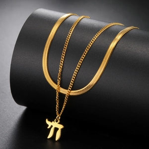 Macro-detail van een dubbellaagse gouden ketting met een Chai-symbool hanger op zwarte houder
