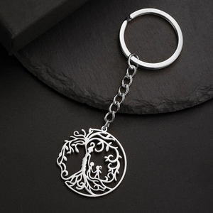 Détail macro du porte-clés arbre de vie en acier inoxydable avec silhouettes sur pierre noire