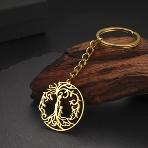 Gros plan détaillé du porte-clés doré pendentif Arbre de Vie sur pierre texturée sombre