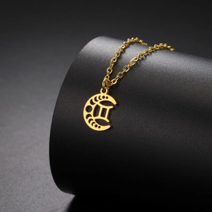 Gros plan détaillé du pendentif lune dorée avec signe des Gémeaux sur un support noir
