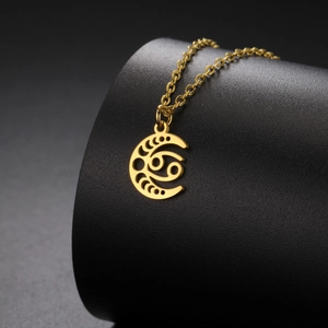 Détail du collier en acier doré avec pendentif lune évidée et signe du zodiaque Cancer
