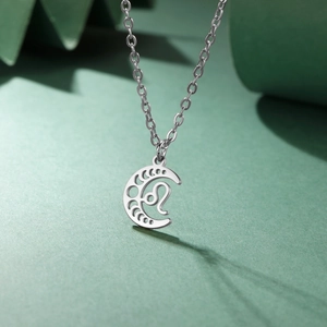 Détail du collier croissant de lune argenté avec signe du lion sur fond vert